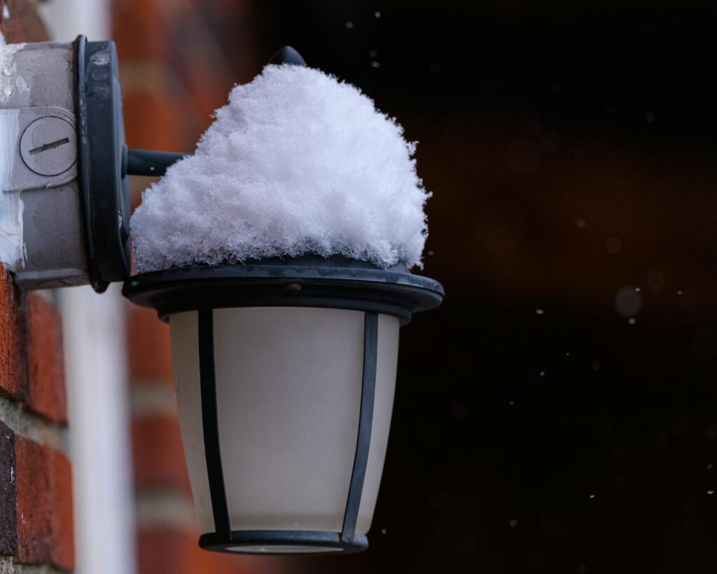 Dise&ntilde;o Beatstore: Linterna exterior cubierta de nieve sobre una pared de ladrillos durante el invie