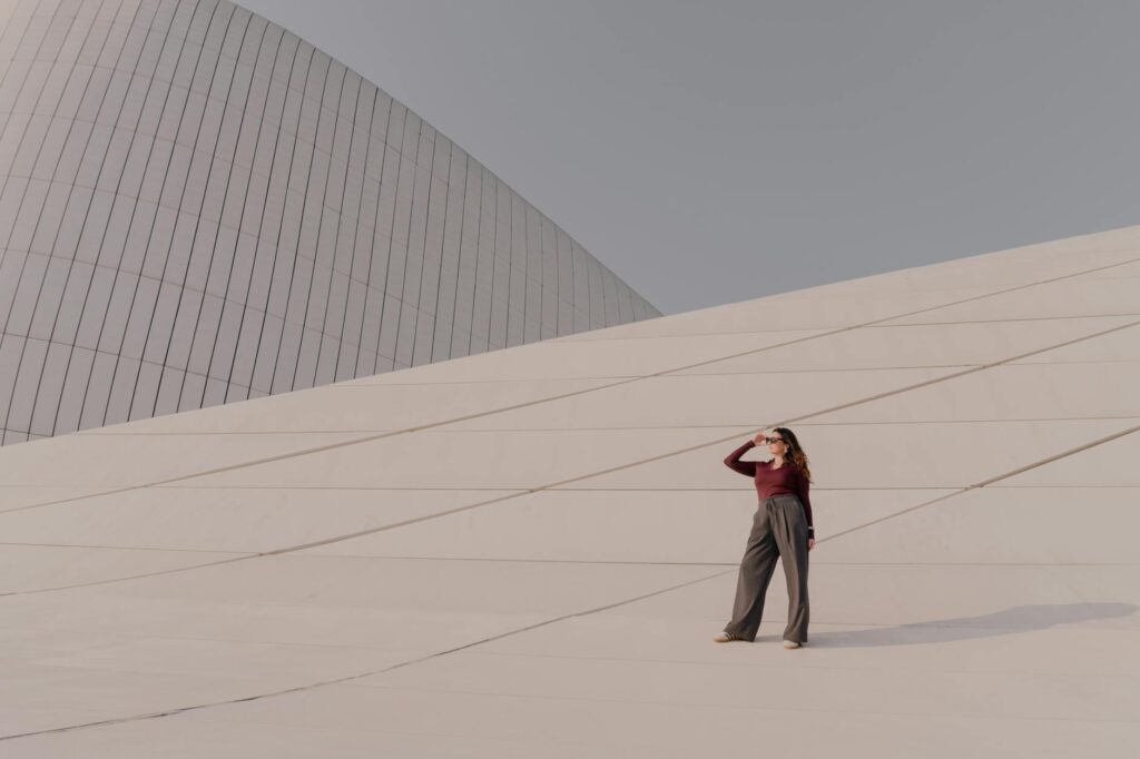 Diseño Beatstore Profesional: Mujer elegante de pie frente a una estructura arquitectónica moderna